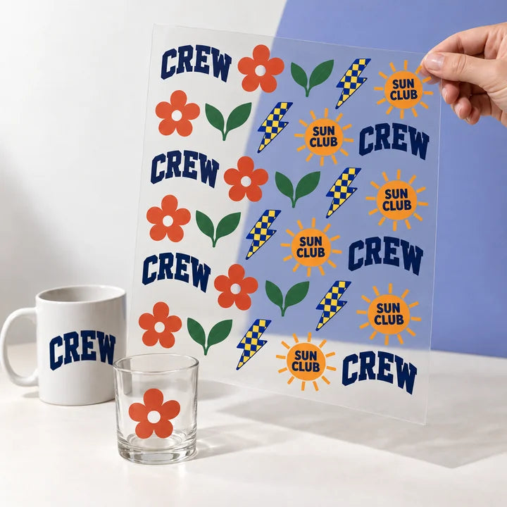 Mockup: hand holding up a finished UV-DTF decal sheet, with a glass and a mug as application examples